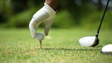 person teeing up a golf ball